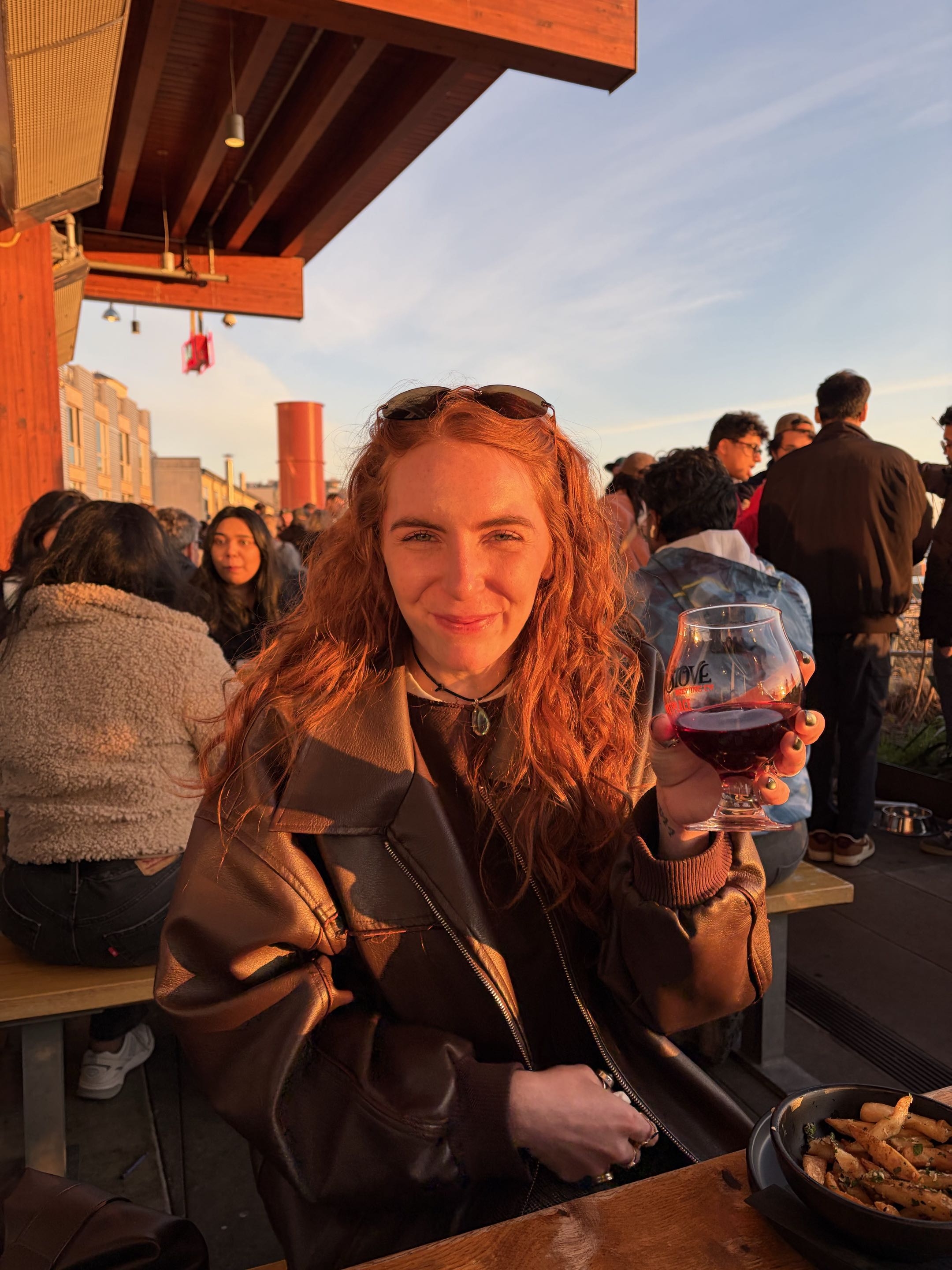 Owner two seated outdoors holding a glass at sunset
